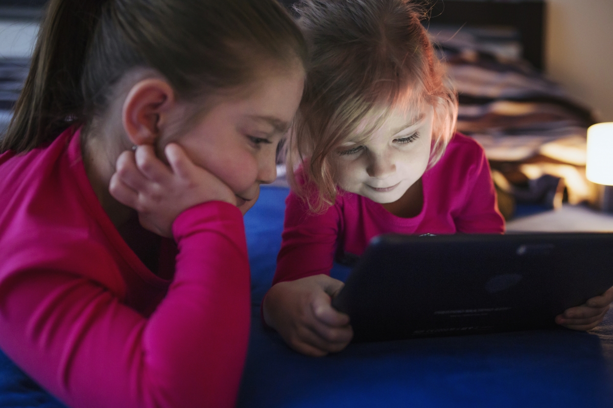 Image 1: Two girls watching video on a tablet.